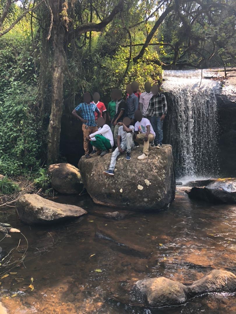 Eine Gruppe steht und sitzt auf einem Felsen neben einem Wasserfall