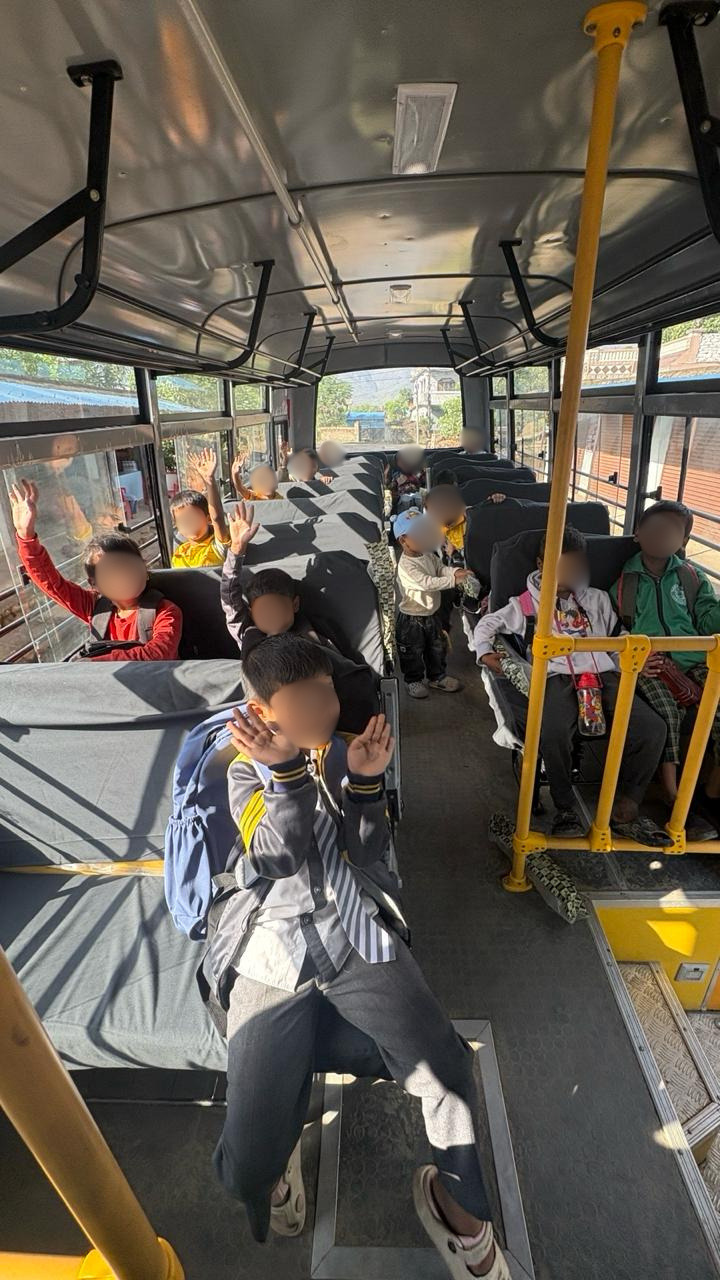 Kinder winken im neuen Schulbus der Empower International School